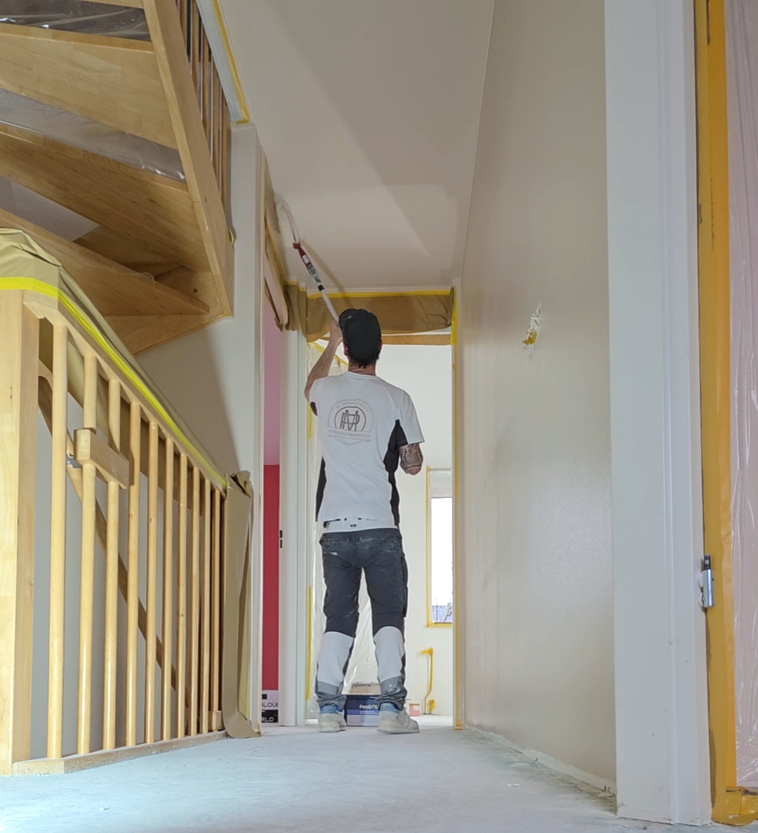 Vakman rolt een plafond in een afgeplakte gang